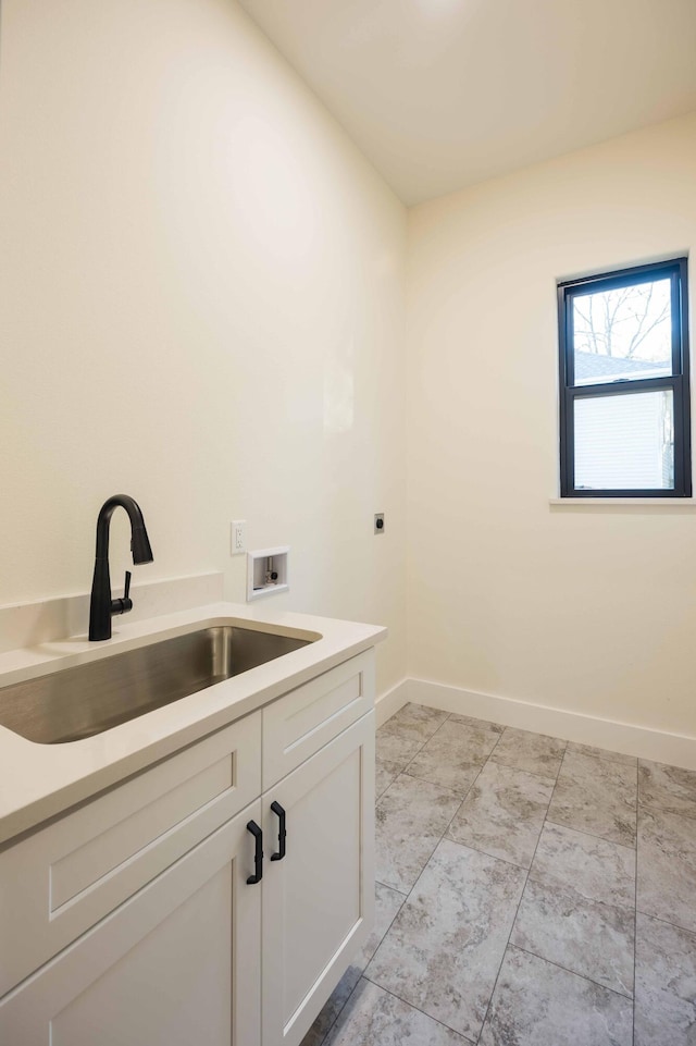 clothes washing area with cabinet space, washer hookup, a sink, electric dryer hookup, and baseboards