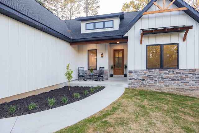 property entrance with roof with shingles, covered porch, board and batten siding, and stone siding