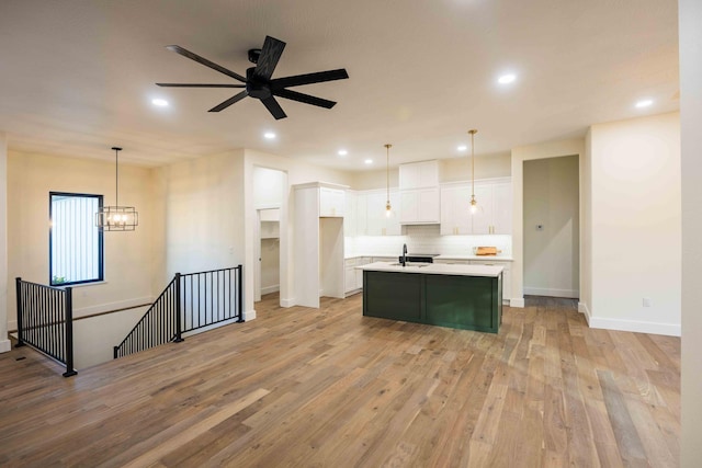 kitchen with decorative backsplash, white cabinetry, a sink, light countertops, and light wood-style flooring