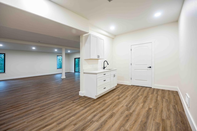 interior space featuring recessed lighting, baseboards, dark wood-style floors, and a sink
