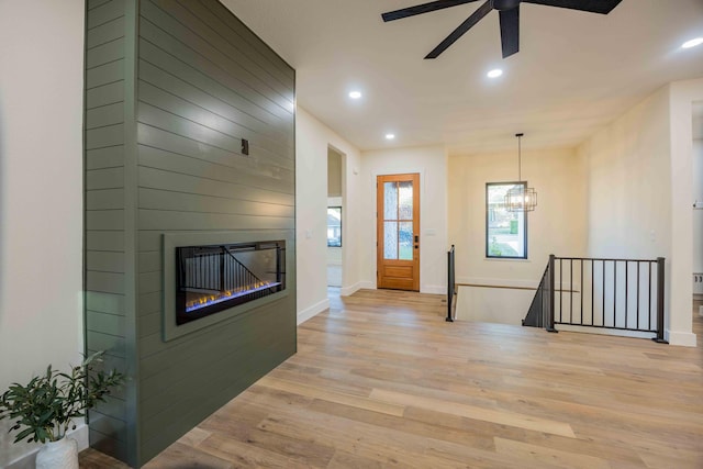 foyer featuring recessed lighting, light wood finished floors, ceiling fan with notable chandelier, and a fireplace