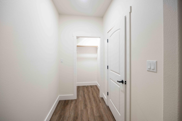 corridor featuring baseboards and dark wood-type flooring