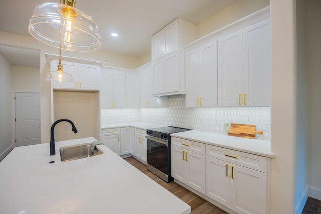 kitchen with white cabinets, a sink, light countertops, range with electric cooktop, and decorative backsplash