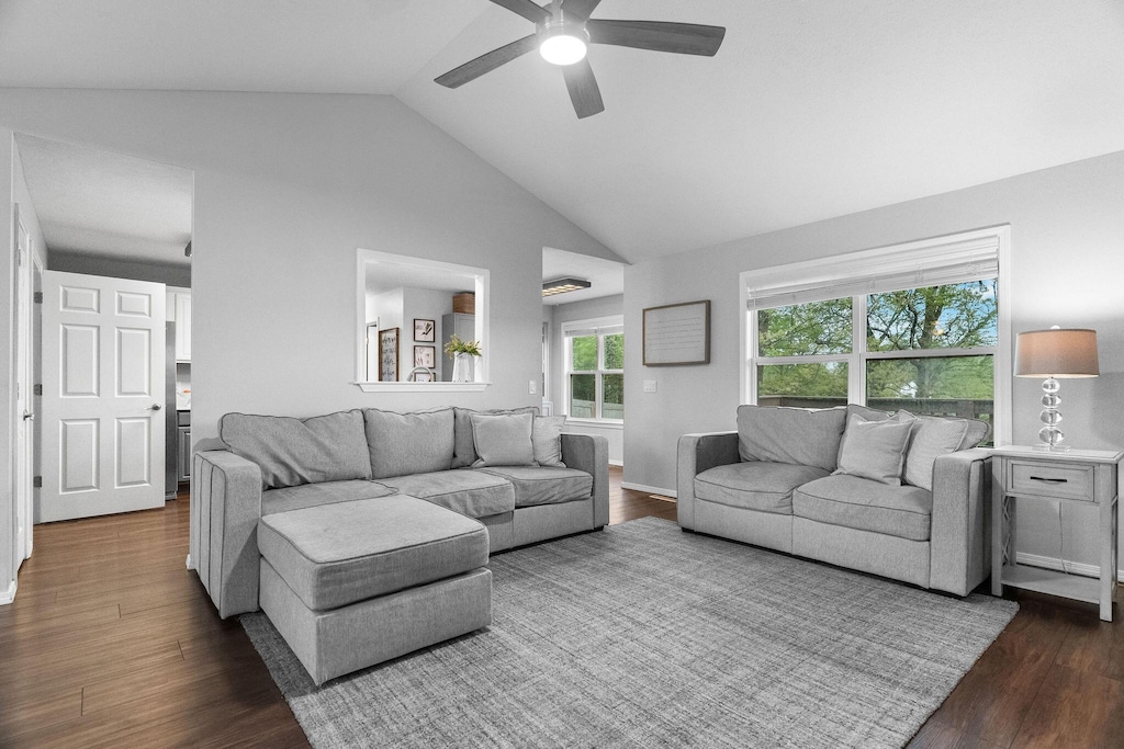 living room with dark wood-style flooring, ceiling fan, and high vaulted ceiling