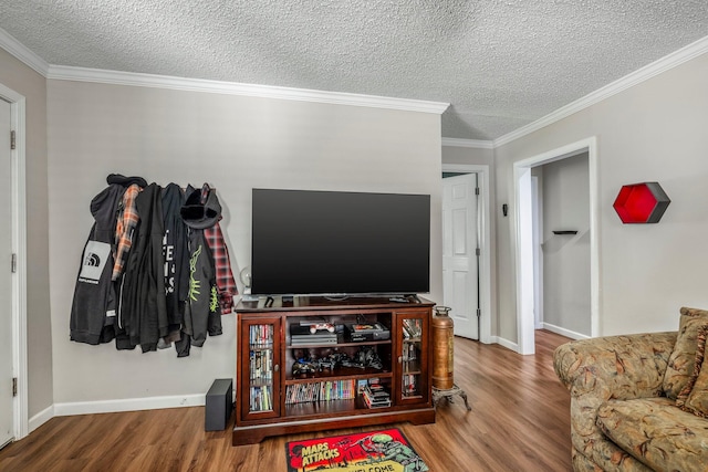living room with a textured ceiling, ornamental molding, baseboards, and wood finished floors