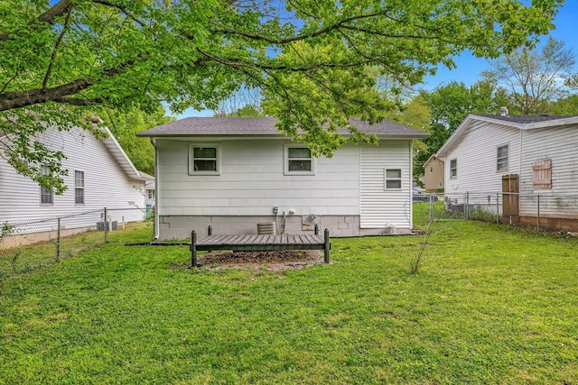 rear view of house featuring a lawn, fence, and a shingled roof