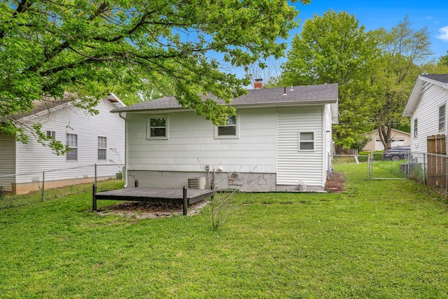 rear view of house with a fenced backyard, a wooden deck, a chimney, and a lawn