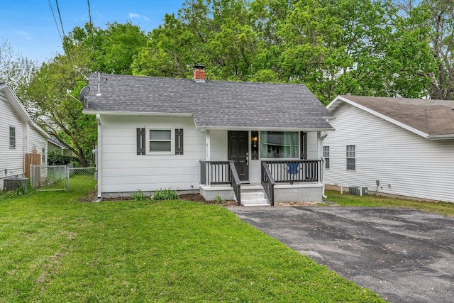 bungalow-style home with fence, a front yard, a chimney, a shingled roof, and a porch