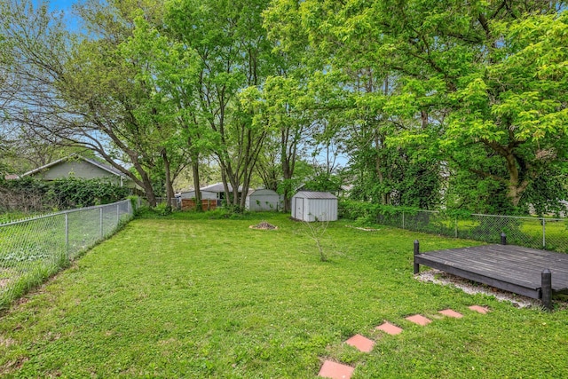 view of yard featuring a fenced backyard, a storage unit, an outdoor structure, and a wooden deck
