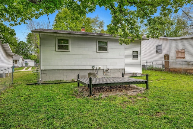 rear view of property with a fenced backyard, a chimney, and a yard