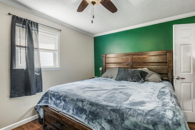 bedroom with ceiling fan, a textured ceiling, wood finished floors, baseboards, and ornamental molding
