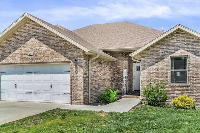 ranch-style home featuring brick siding, a shingled roof, an attached garage, and concrete driveway
