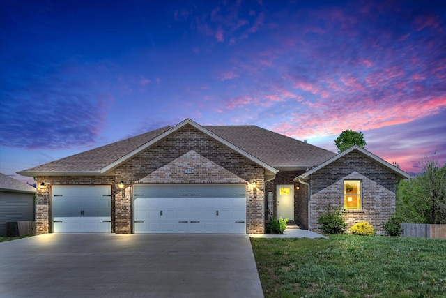 ranch-style house featuring brick siding, a shingled roof, concrete driveway, an attached garage, and a yard