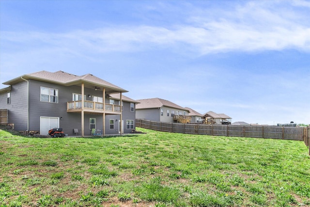 back of house with a fenced backyard, a ceiling fan, a lawn, and a balcony