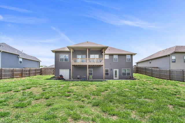 back of property featuring a fenced backyard, a ceiling fan, a lawn, and a balcony