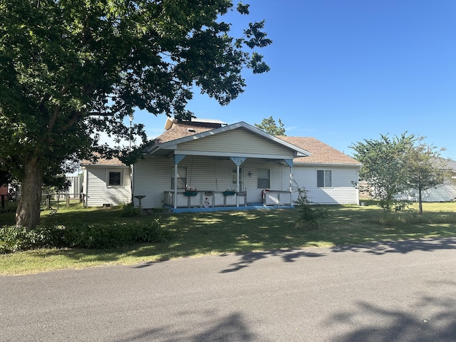 bungalow-style home with a porch, a front lawn, and roof with shingles
