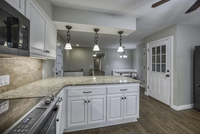kitchen featuring white cabinets, dark wood-style flooring, black microwave, a peninsula, and a ceiling fan