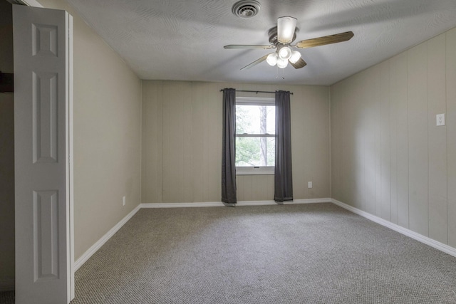 carpeted spare room featuring ceiling fan, visible vents, and baseboards