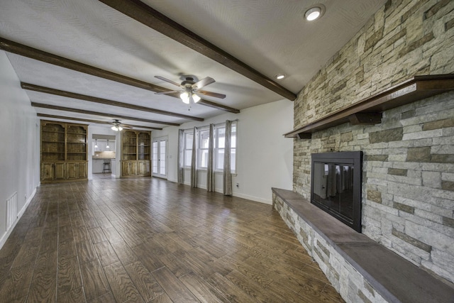 unfurnished living room with dark wood-style flooring, a fireplace, beamed ceiling, baseboards, and ceiling fan