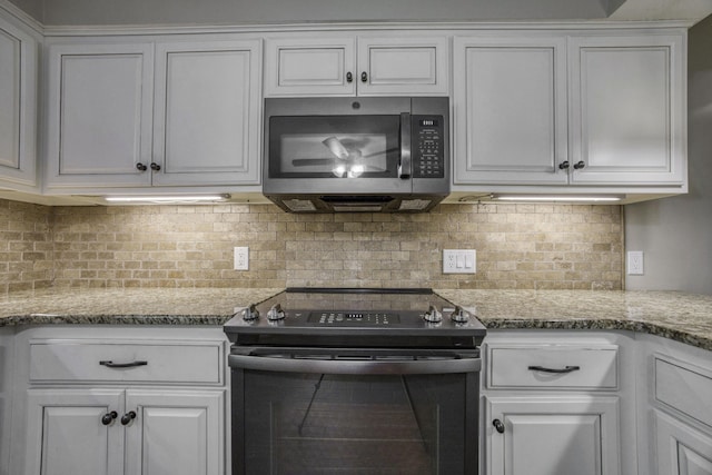 kitchen with white cabinetry, stainless steel microwave, tasteful backsplash, and black range with electric stovetop