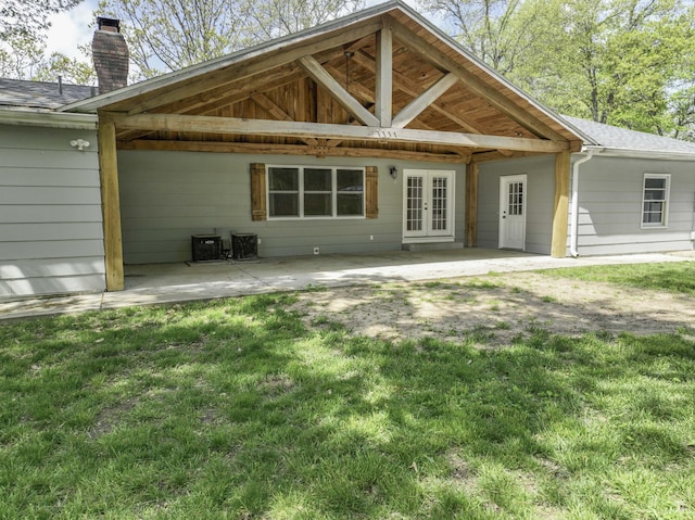 rear view of house with french doors, a chimney, a patio area, a lawn, and a carport