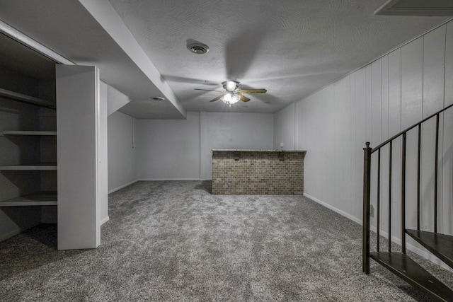 unfurnished living room with carpet flooring, ceiling fan, a textured ceiling, baseboards, and visible vents