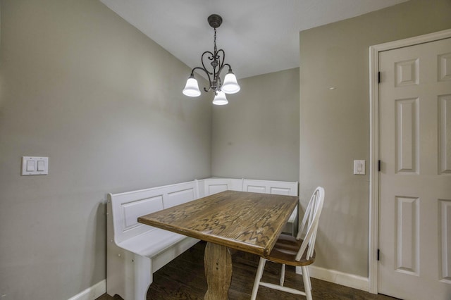 dining space featuring baseboards, dark wood-type flooring, and a notable chandelier