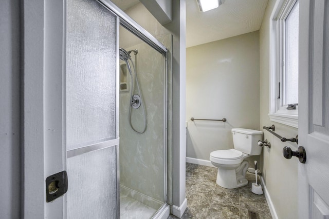 bathroom with baseboards, toilet, and a shower stall