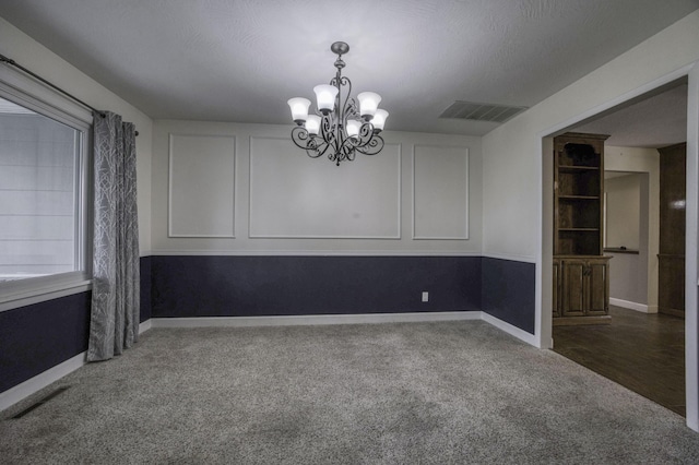 empty room with baseboards, carpet, a notable chandelier, and visible vents