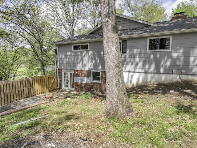 view of property exterior with fence, french doors, a patio area, and a chimney