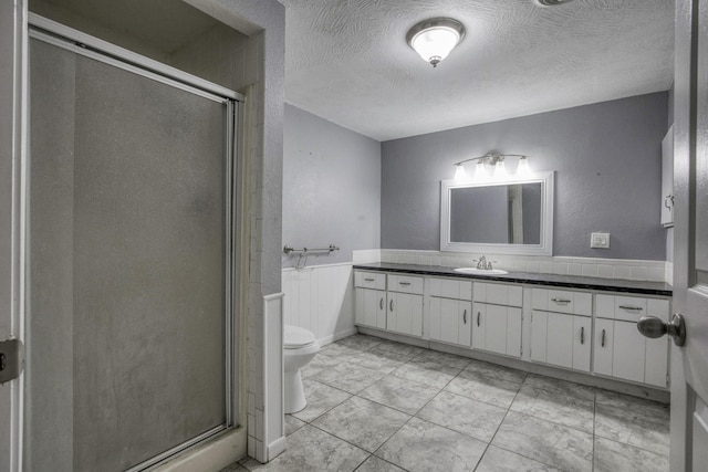full bath featuring vanity, a stall shower, toilet, and a textured ceiling
