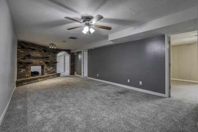 unfurnished living room with baseboards, ceiling fan, a fireplace, and carpet flooring