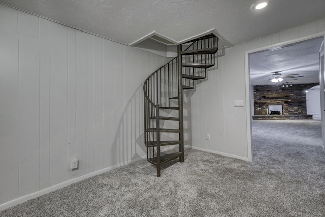 stairway featuring a brick fireplace, ceiling fan, baseboards, and carpet