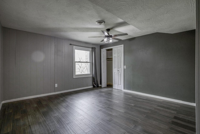 unfurnished bedroom with a textured ceiling, dark wood finished floors, a ceiling fan, baseboards, and a closet