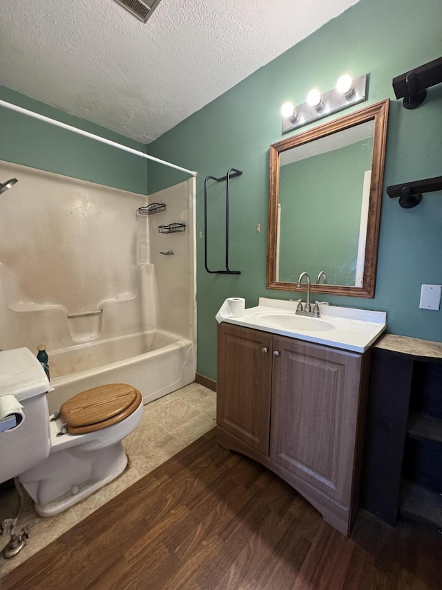 full bath featuring vanity, wood finished floors, toilet, bathtub / shower combination, and a textured ceiling