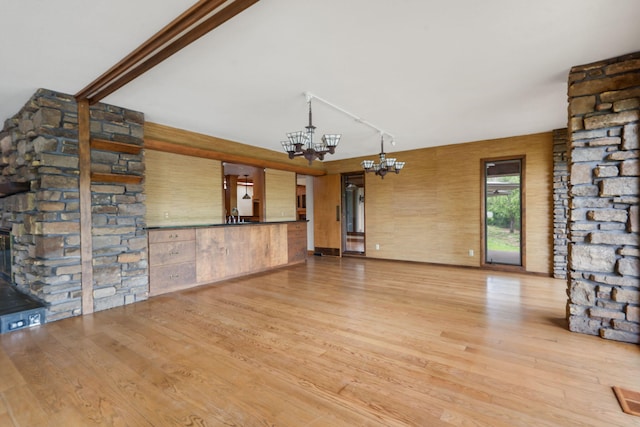 unfurnished living room featuring an inviting chandelier and wood finished floors