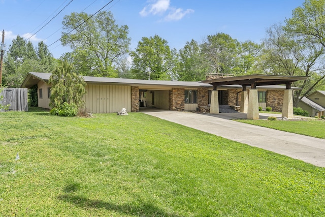 rear view of property featuring a carport, a yard, driveway, and stone siding