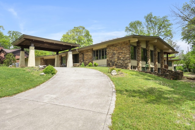 view of front of house with a front lawn, stone siding, and concrete driveway
