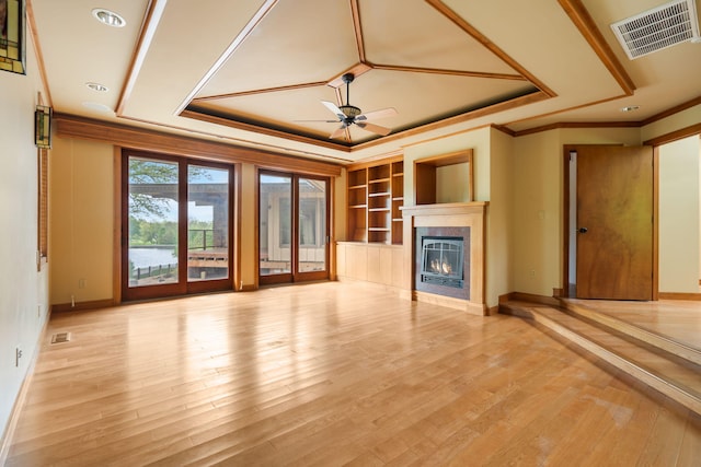 unfurnished living room with crown molding, a raised ceiling, ceiling fan, and visible vents