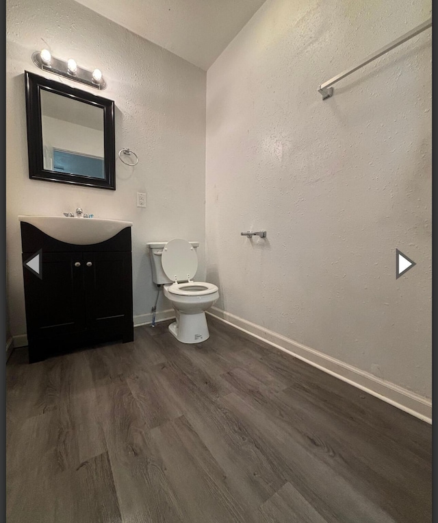 1207 W Florida St, Springfield, MO 65803 - half bath with wood finished floors, vanity, baseboards, toilet, and a textured wall