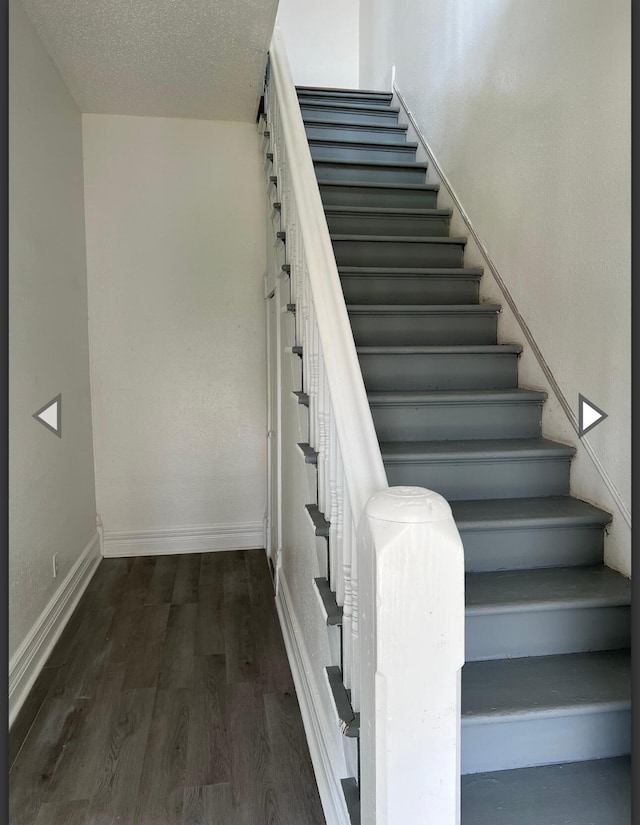staircase with baseboards, a textured ceiling, and wood finished floors