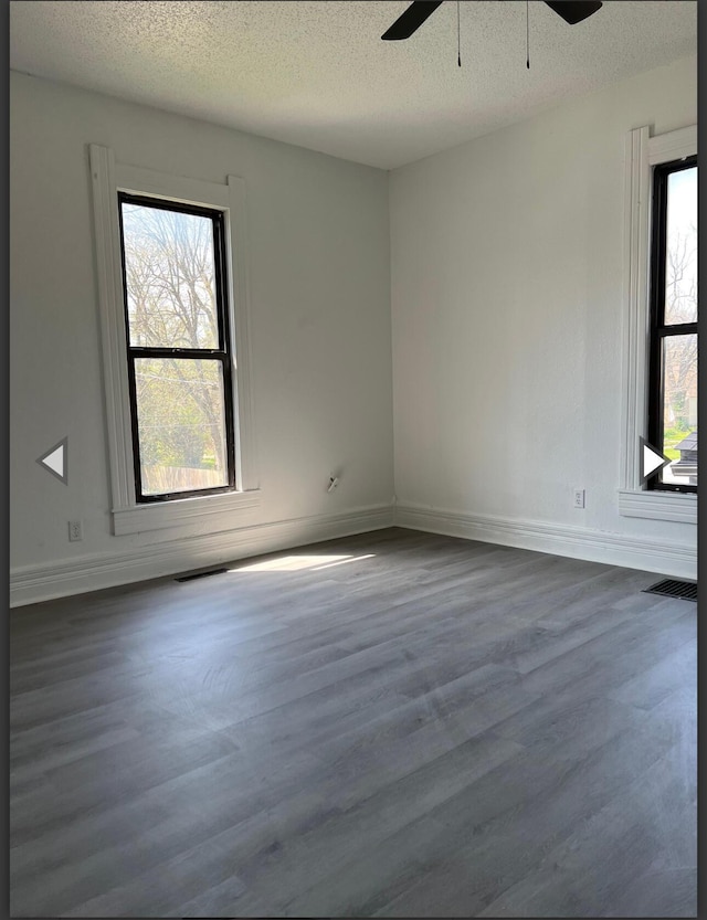 unfurnished room featuring a ceiling fan, a textured ceiling, baseboards, and dark wood-type flooring