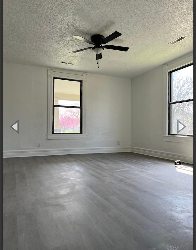 unfurnished room with a ceiling fan, a textured ceiling, visible vents, and baseboards