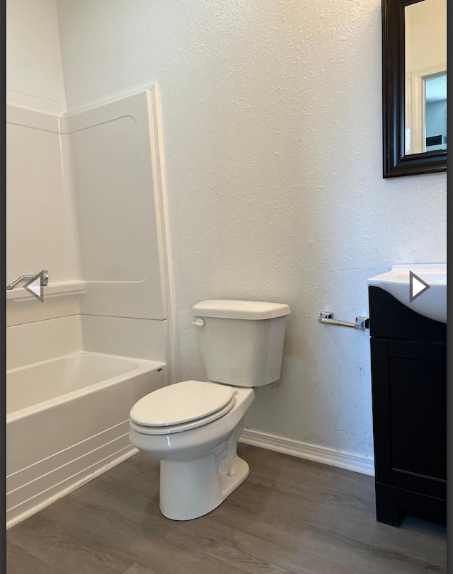 bathroom featuring vanity, toilet, baseboards, tub / shower combination, and wood finished floors