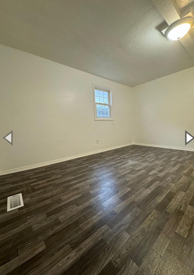 2105 N Elizabeth Ave, Springfield, MO 65803 - basement with baseboards, visible vents, a textured ceiling, and dark wood-type flooring