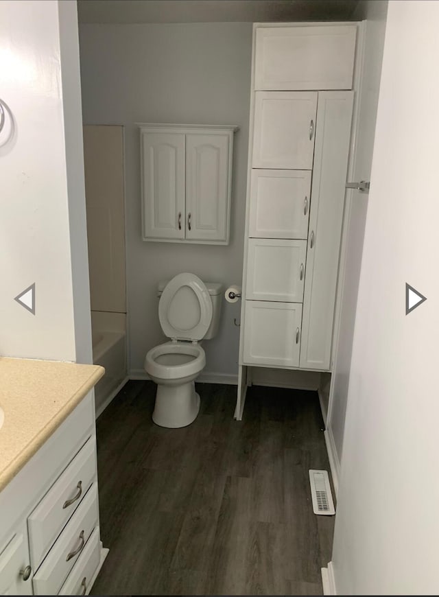 full bathroom with a bath, visible vents, wood finished floors, vanity, and baseboards