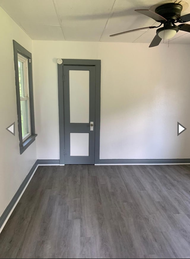 spare room featuring ceiling fan, baseboards, and dark wood-type flooring