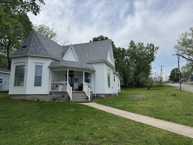 victorian house featuring a shingled roof, a porch, and a front lawn