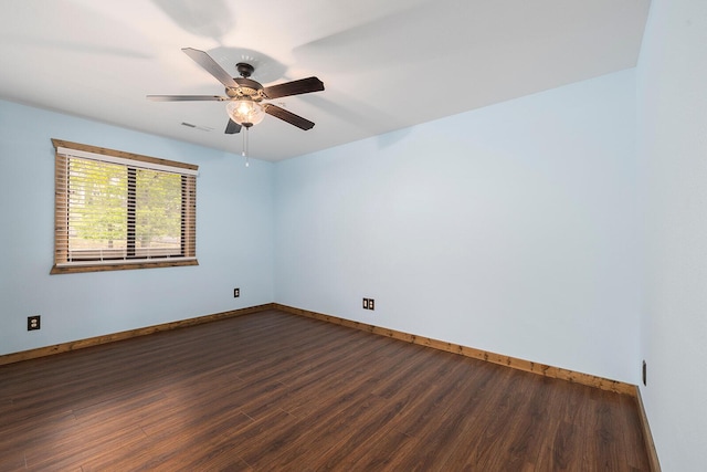 empty room featuring baseboards, dark wood finished floors, and visible vents