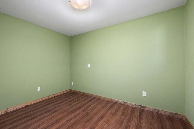 unfurnished room with baseboards and dark wood finished floors